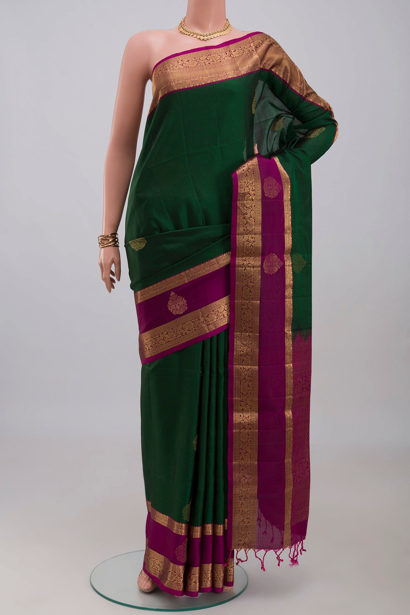 Bottle Green Soft Silk Saree with Zari Butta on the body and Zari Border.  displayed on a mannequin