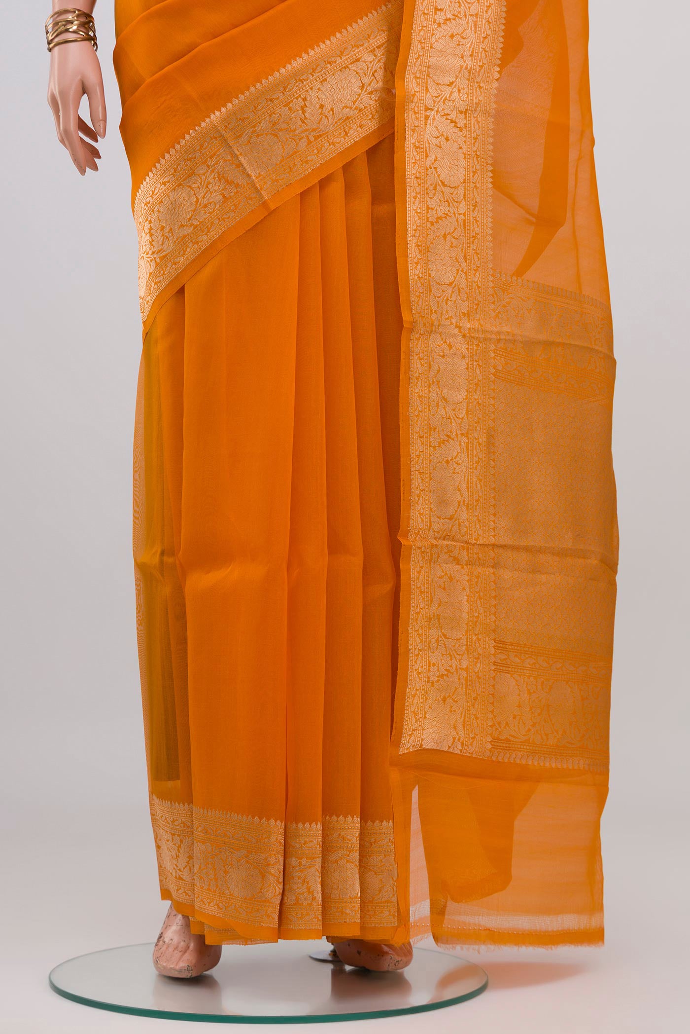 Pleats and pallu of Orange Organza Silk Saree with Plain Body and Zari Border. 