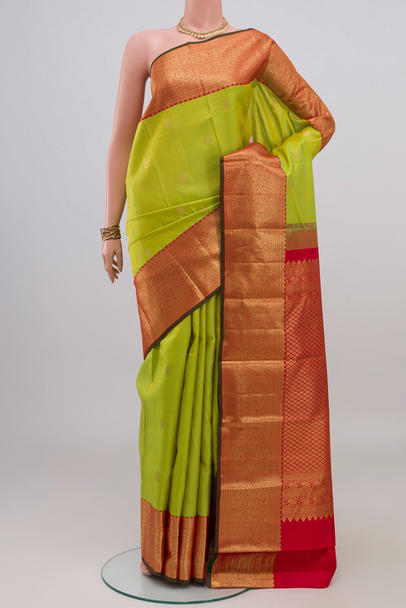 Parrot Green Kanjivaram Silk Saree with Zari Butta on the body and Zari Border.  displayed on a mannequin