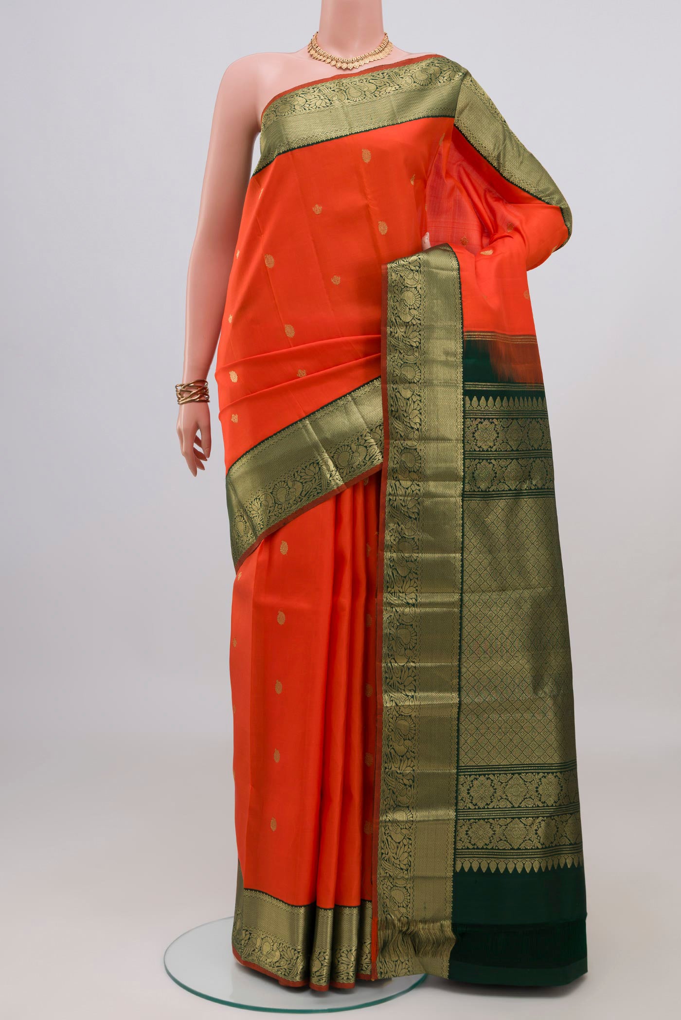 Orange Kanjivaram Silk Saree with Zari Butta on the body and Zari Border.  displayed on a mannequin