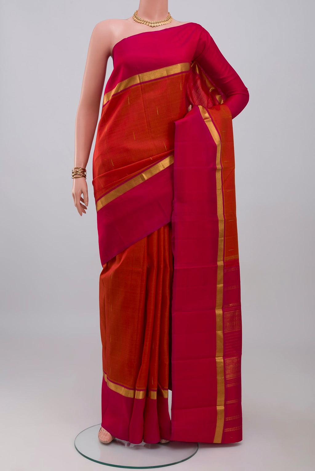 Brick Orange Kanjivaram Silk Saree with Zari Butta on the body and Zari Border.  displayed on a mannequin