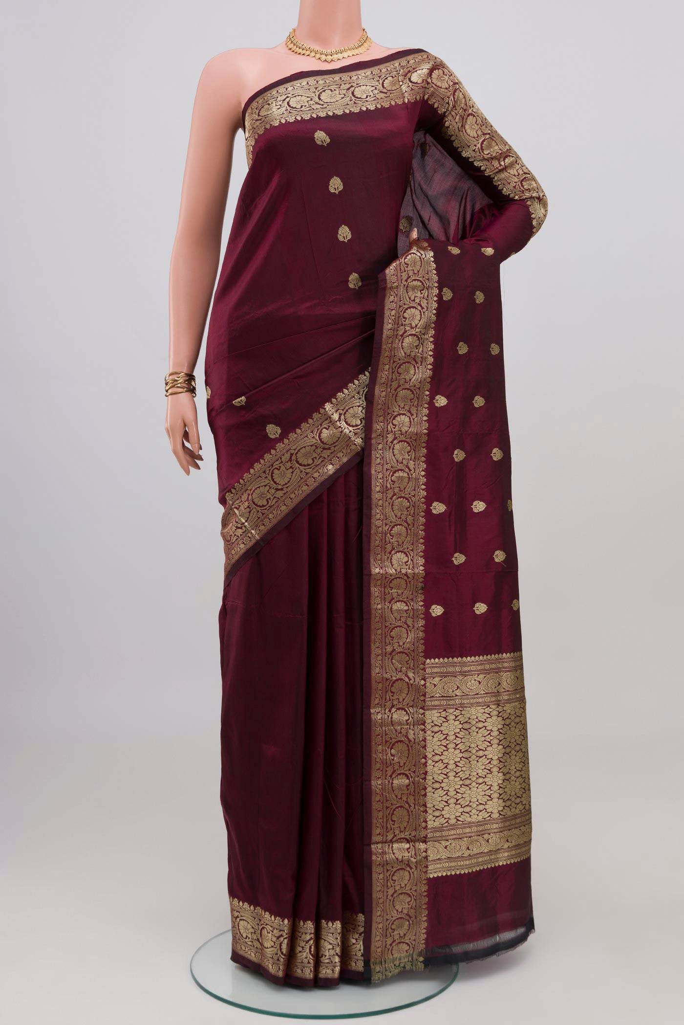 Maroon Banarasi Katan Silk Saree with Zari Butta on the body and Zari Border.  displayed on a mannequin
