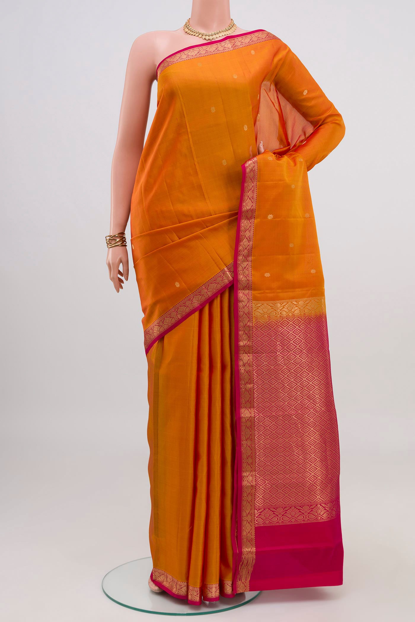 Mustard Kanchipuram Silk Saree with Zari Butta on the body and Zari Border.  displayed on a mannequin