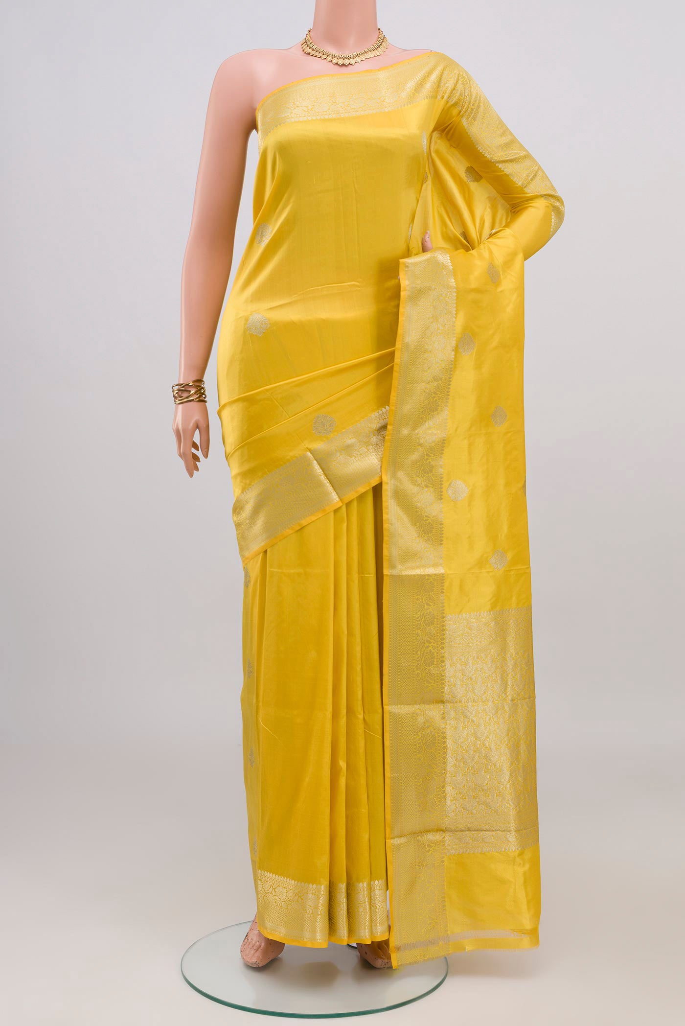 Lemon Yellow Banarasi Katan Silk Saree with Zari Butta on the body and Zari Border.  displayed on a mannequin