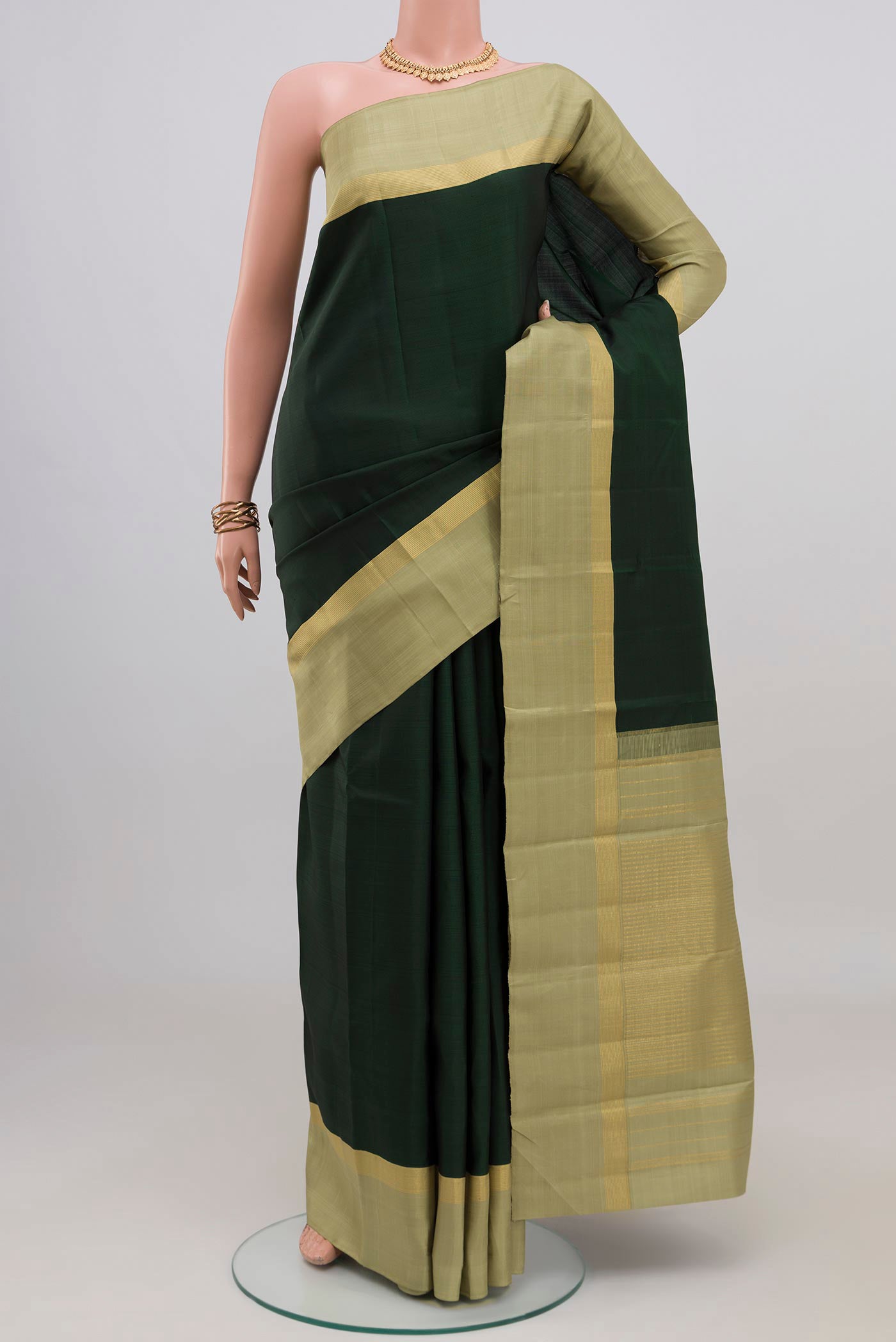 Bottle Green Kanjivaram Silk Saree with Plain Body and Plain Border.  displayed on a mannequin