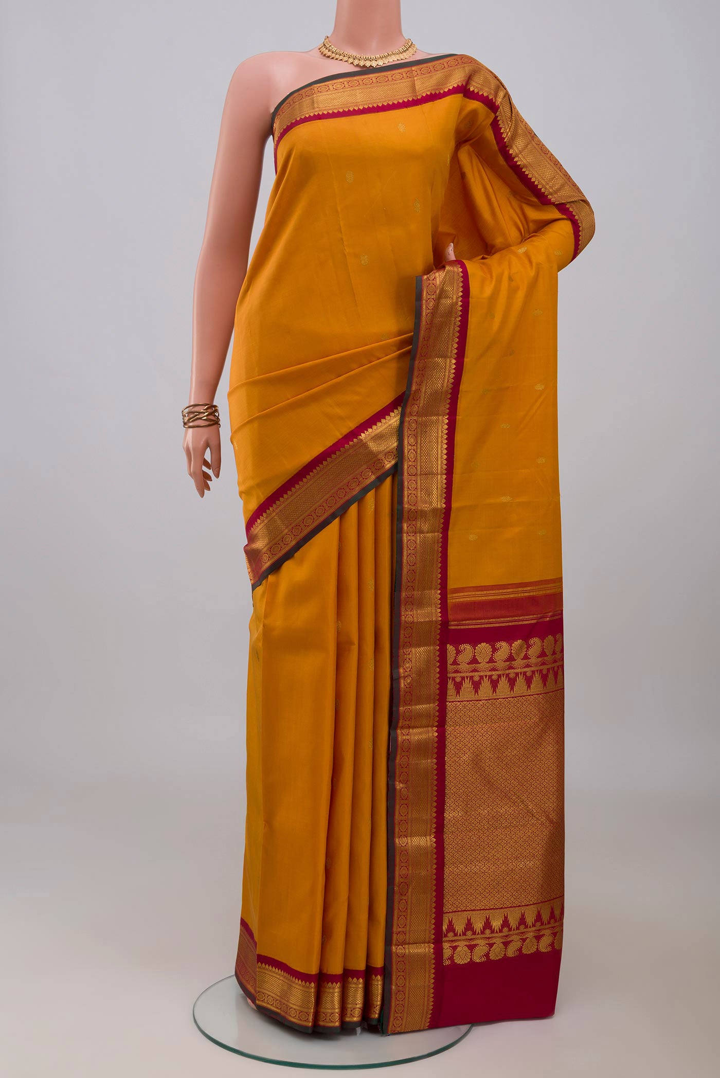 Yellow Kanchipuram Silk Saree with Zari Butta on the body and Zari Border.  displayed on a mannequin