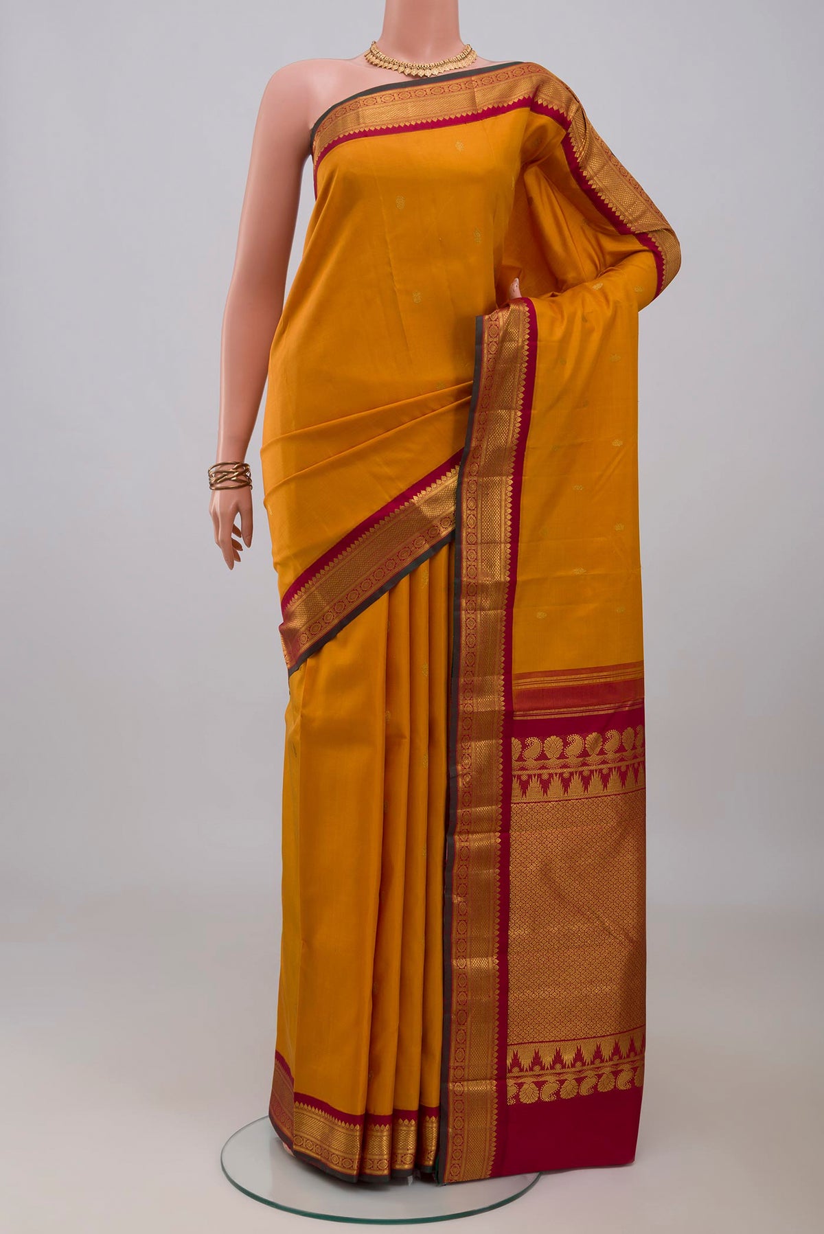 Yellow Kanchipuram Silk Saree with Zari Butta on the body and Zari Border.  displayed on a mannequin