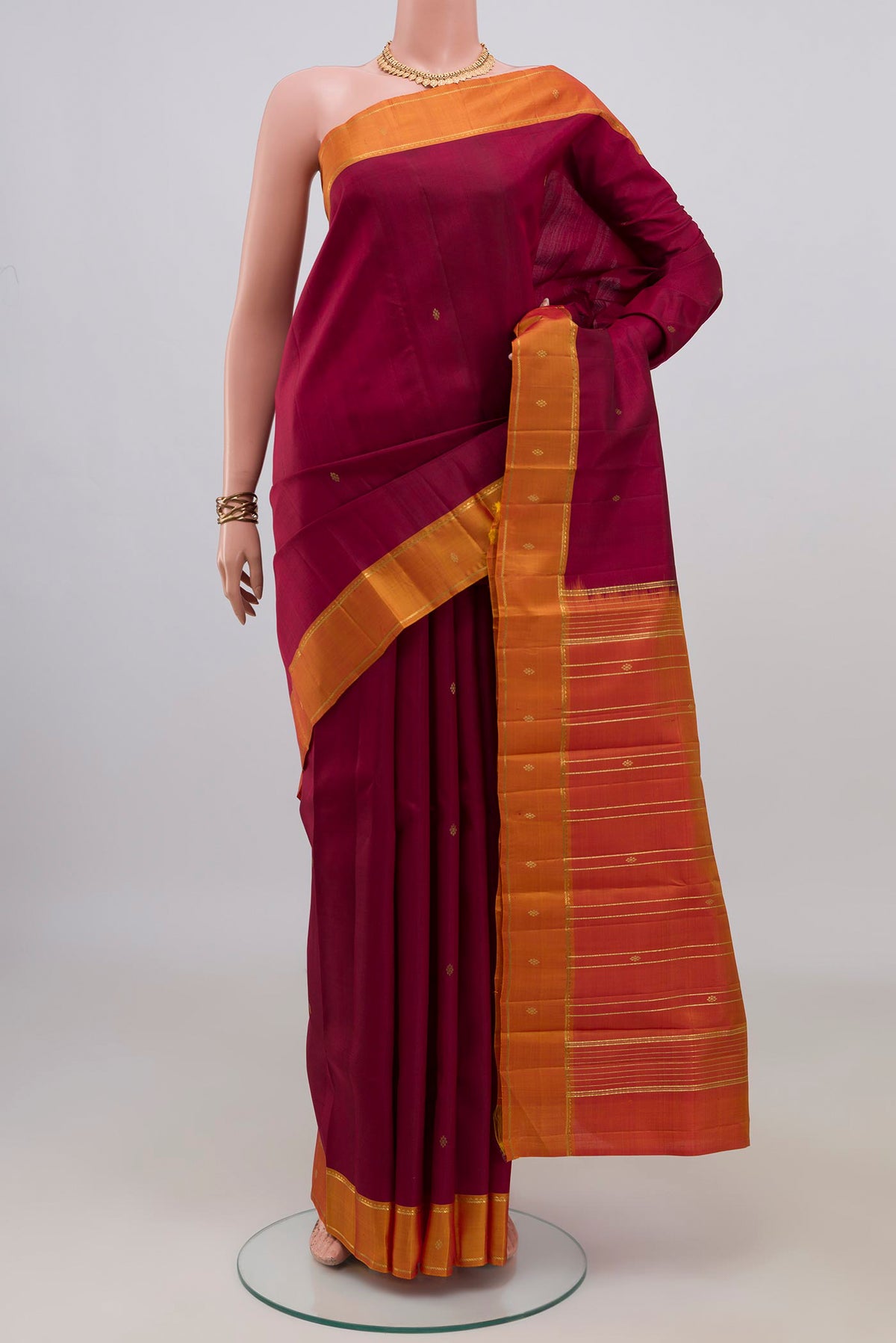 Pure Silk Maroon Kanchipuram Saree with Zari Butta on the body and Thin Zari Line.  displayed on a mannequin