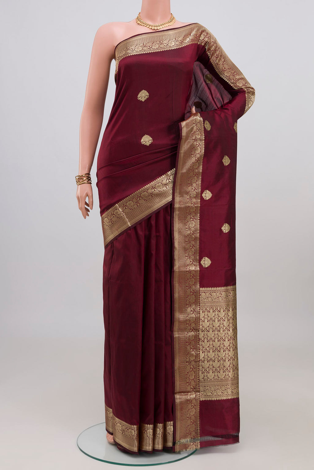 Maroon Banarasi Katan Silk Saree with Zari Butta on the body and Zari Border.  displayed on a mannequin