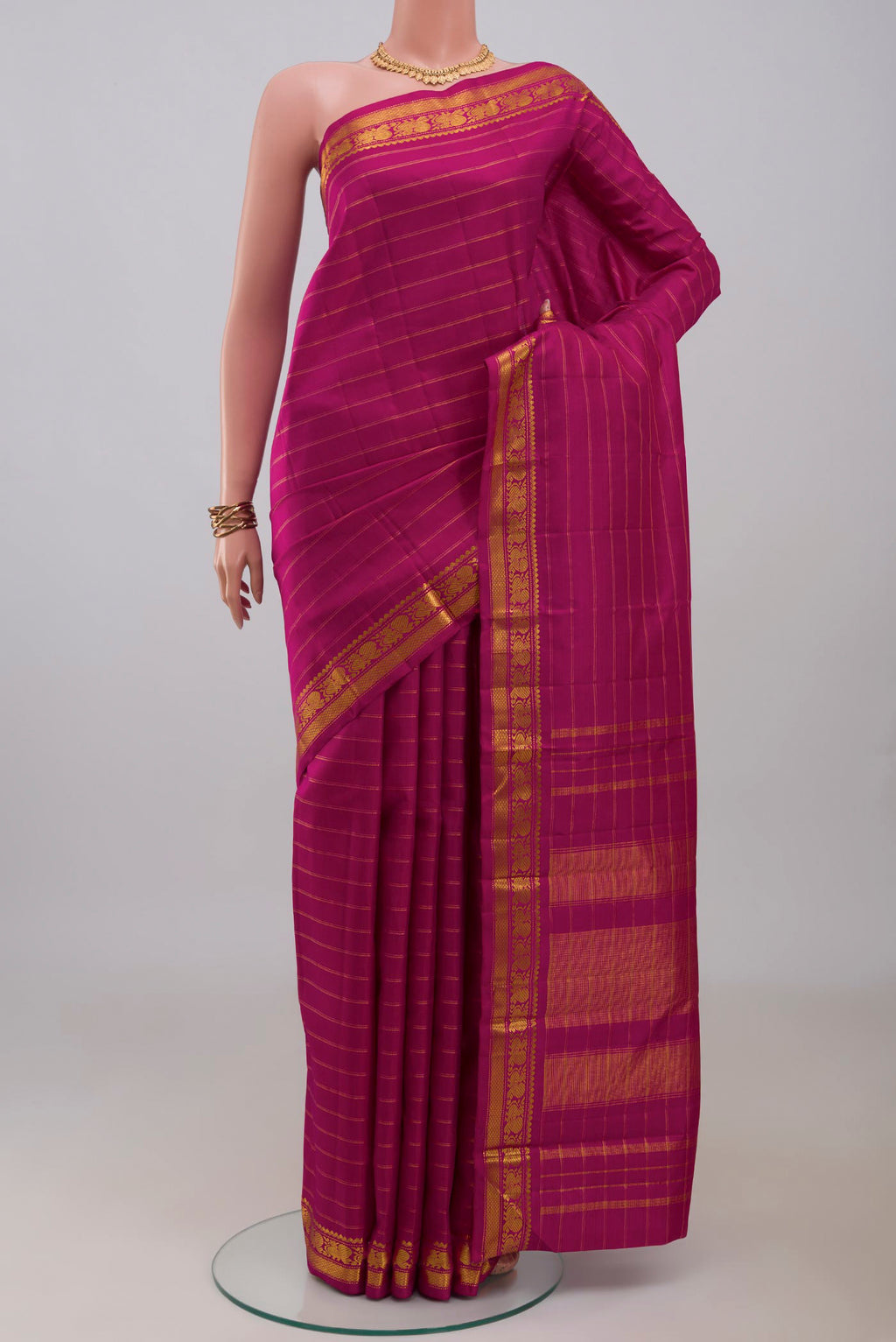 Magenta Kanchipuram Silk Saree with Stripes on the body and Zari Border.  displayed on a mannequin