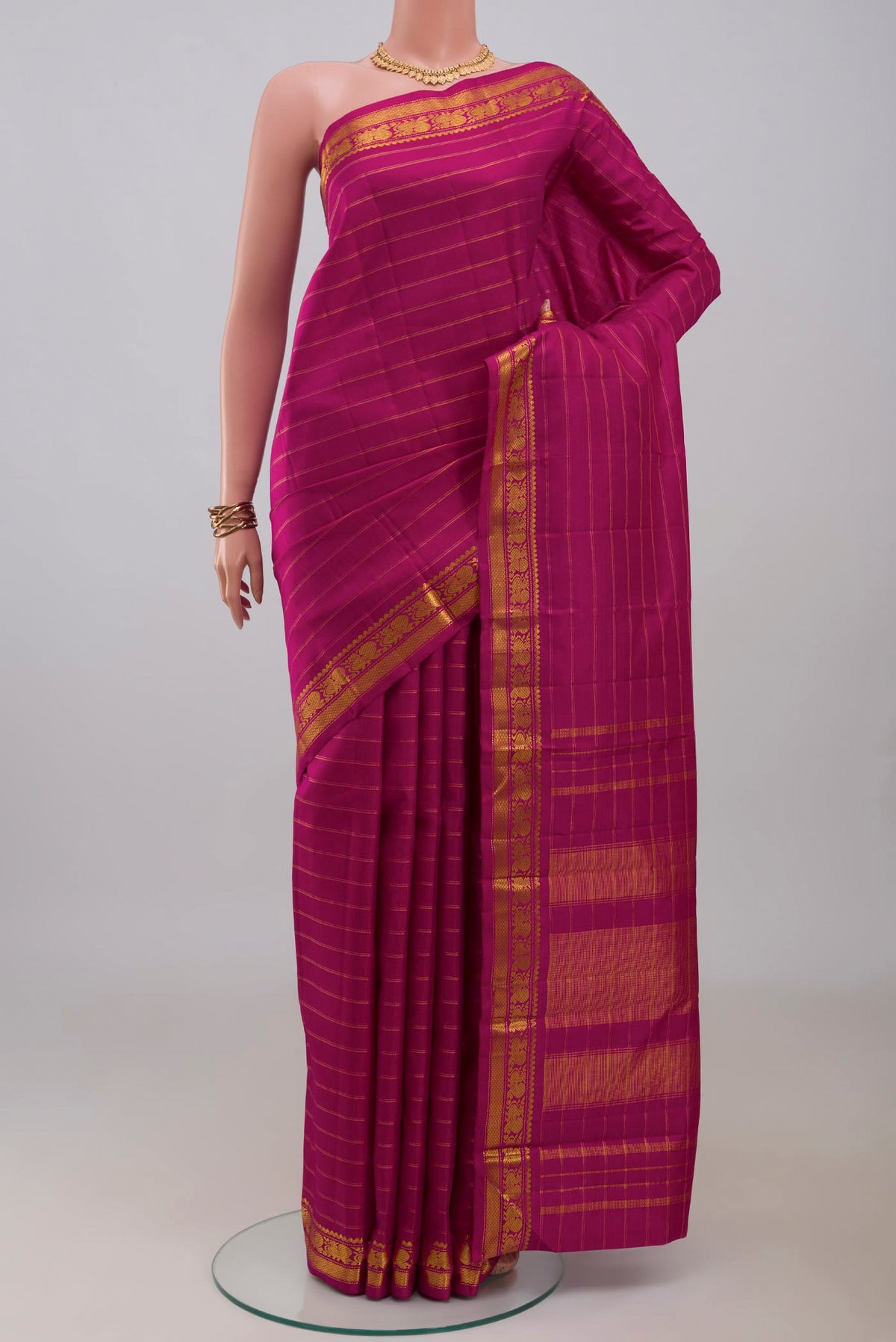 Magenta Kanchipuram Silk Saree with Stripes on the body and Zari Border.  displayed on a mannequin