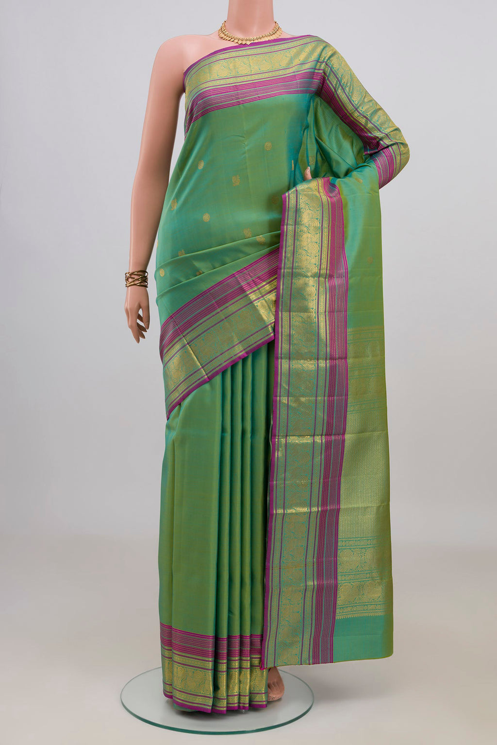 Pure Silk Green Kanjivaram Saree with Zari Butta on the body and Zari Border.  displayed on a mannequin