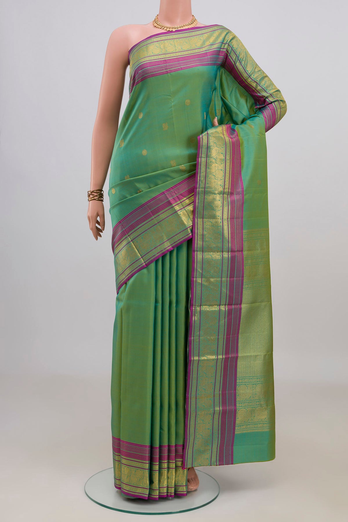 Pure Silk Green Kanjivaram Saree with Zari Butta on the body and Zari Border.  displayed on a mannequin