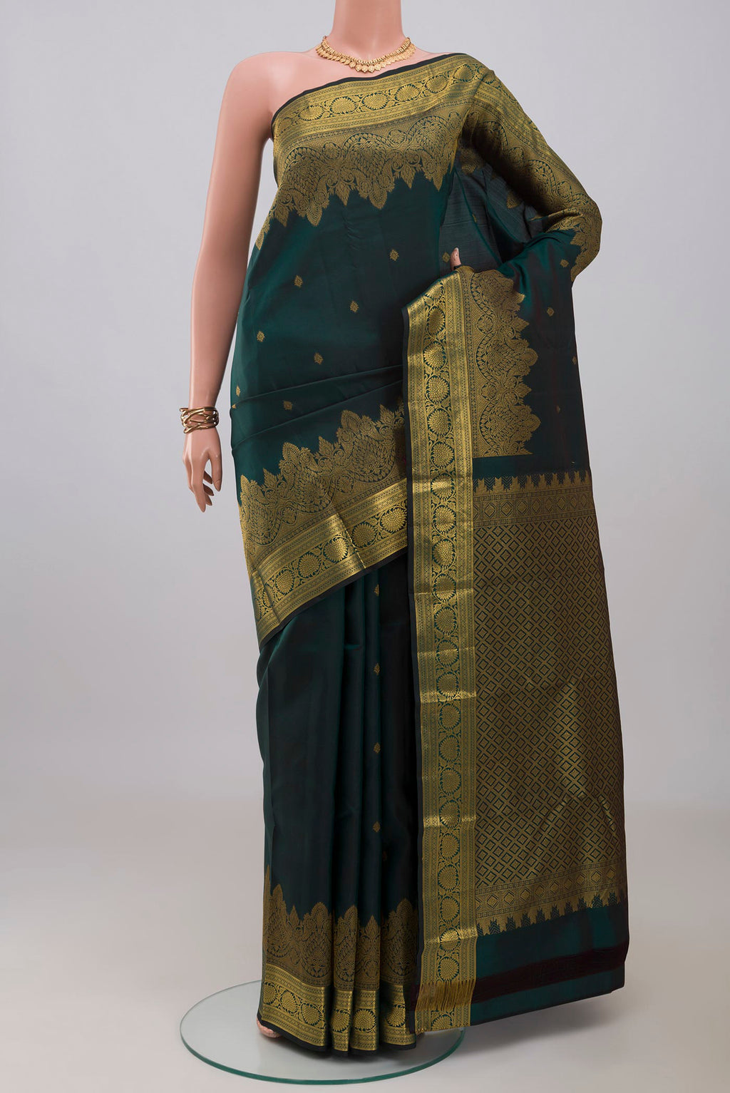 Bottle Green Kanchipuram Silk Saree with Zari Butta on the body and Zari Border.  displayed on a mannequin