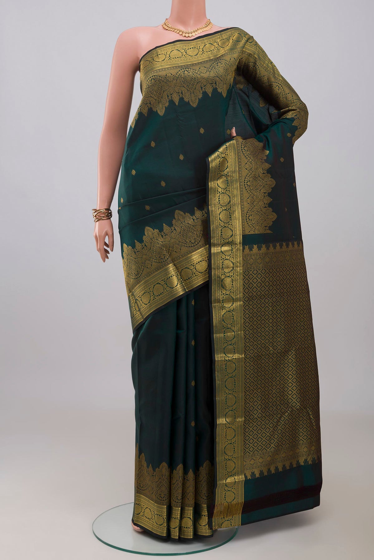 Bottle Green Kanchipuram Silk Saree with Zari Butta on the body and Zari Border.  displayed on a mannequin