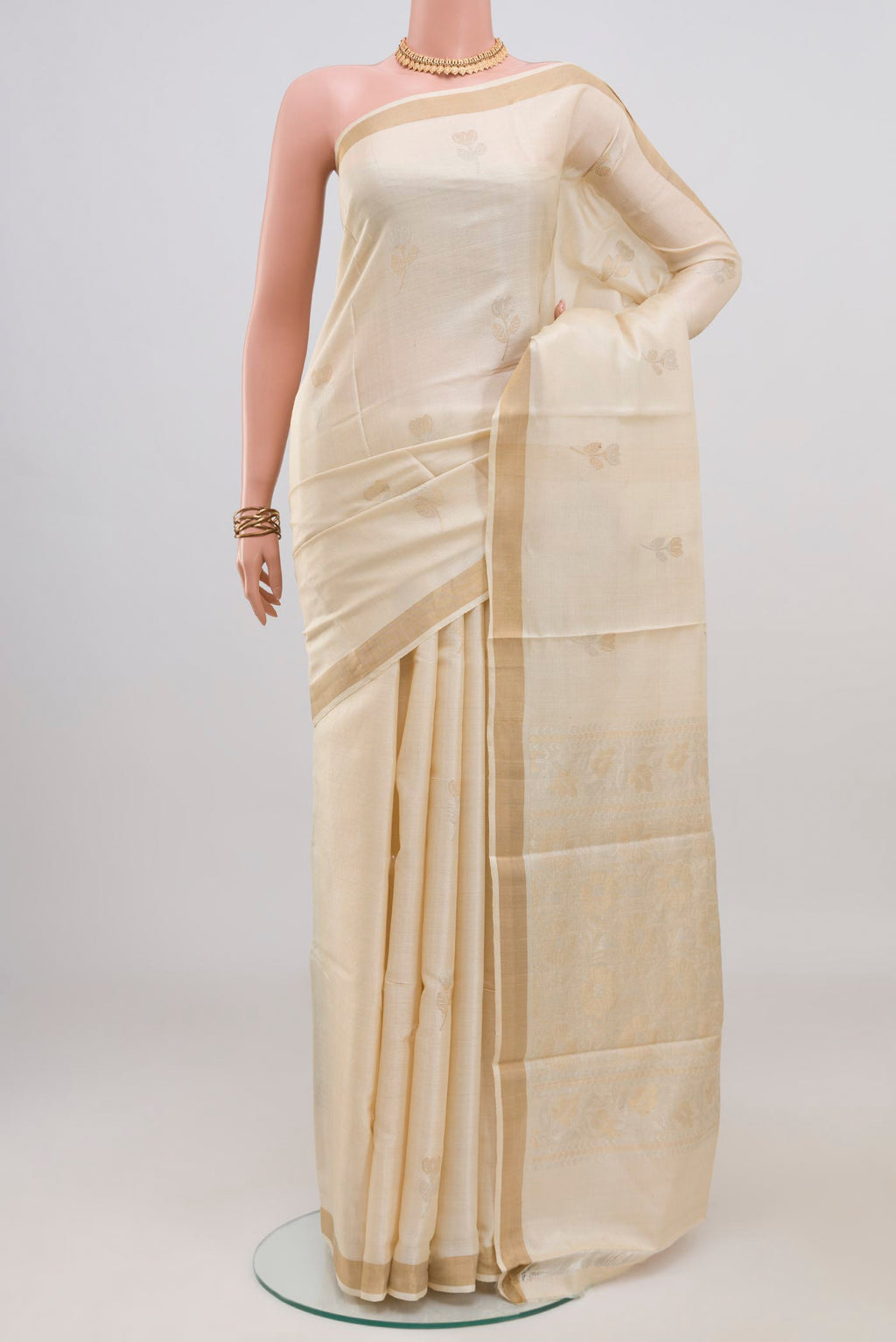 Cream Tussar Silk Saree with Zari Butta on the body and Zari Border.  displayed on a mannequin