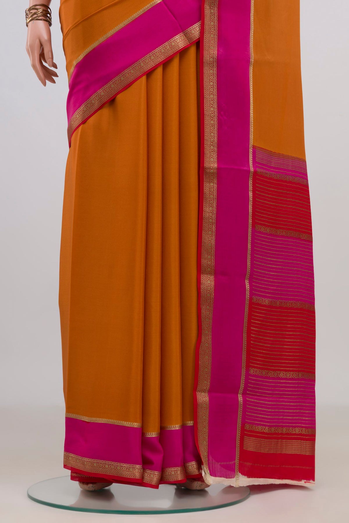 Pleats and pallu of Orange Mysore Crepe Saree with Plain Body and Zari Border. 