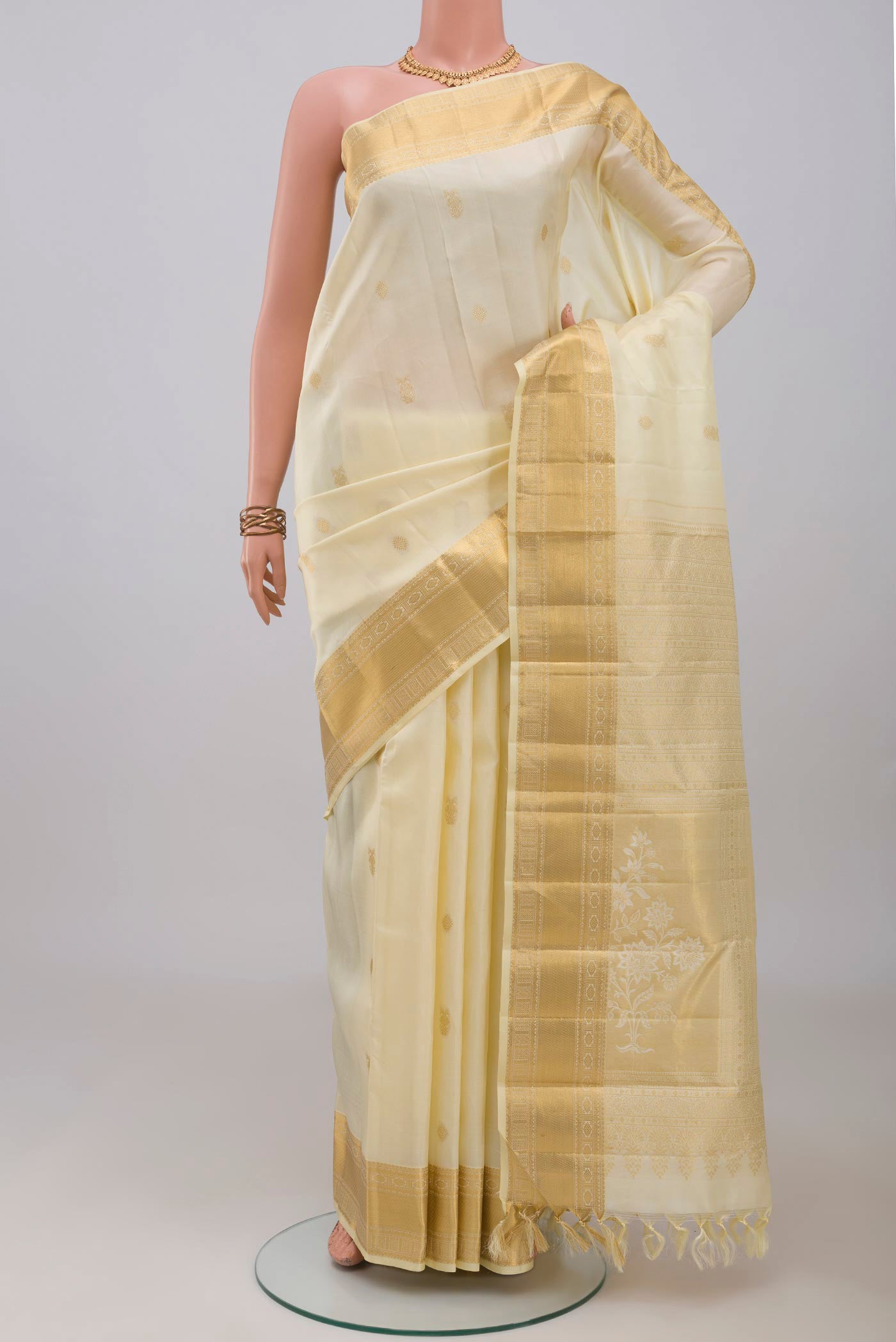 Cream Kanchipuram Silk Saree with Zari Butta on the body and Zari Border.  displayed on a mannequin