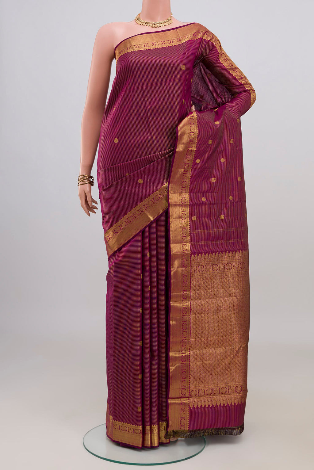 Magenta Kanchipuram Silk Saree with Zari Butta on the body and Zari Border.  displayed on a mannequin