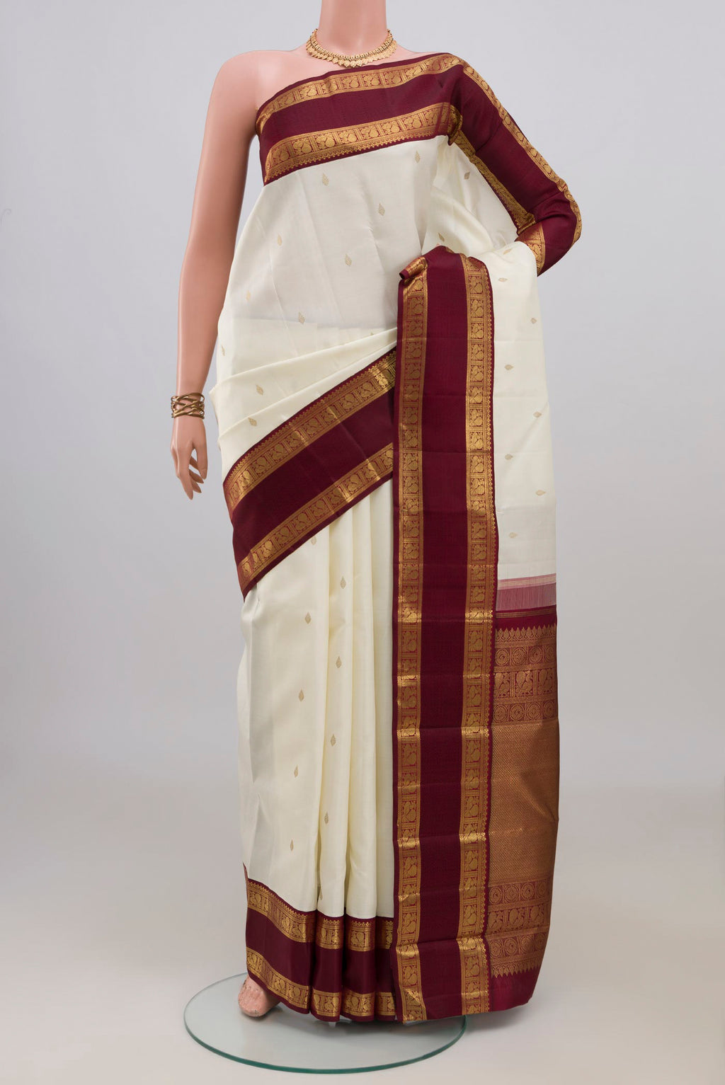 Pure Silk Pure Zari Off White Kanjivaram Saree with Zari Butta on the body and Zari Border.  displayed on a mannequin
