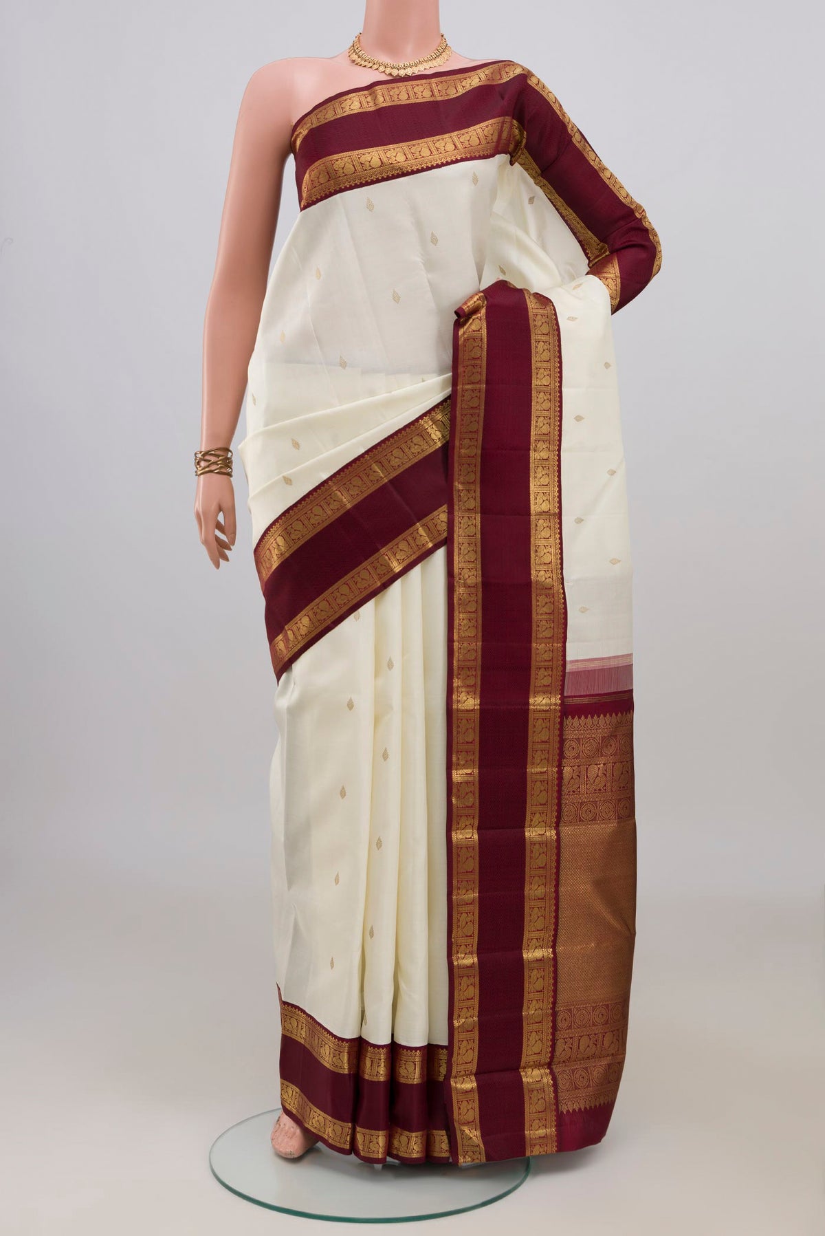 Pure Silk Pure Zari Off White Kanjivaram Saree with Zari Butta on the body and Zari Border.  displayed on a mannequin