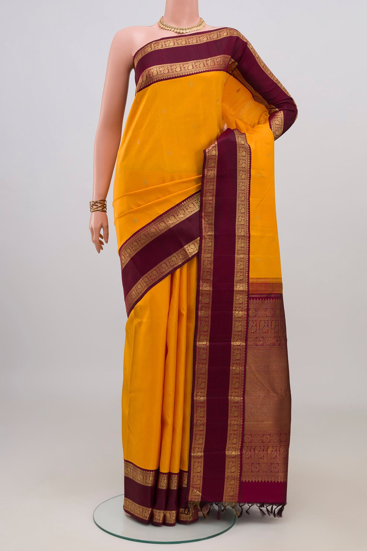 Pure Silk Pure Zari Yellow Kanjivaram Saree with Zari Butta on the body and Zari Border.  displayed on a mannequin