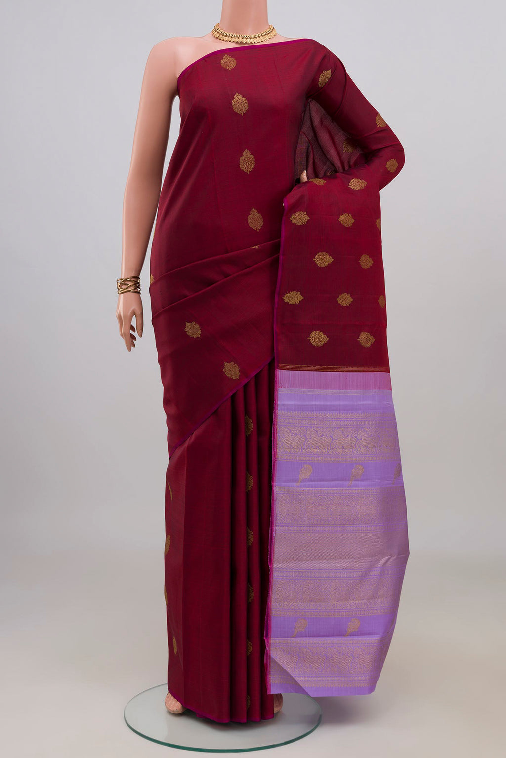 Pure Silk Pure Zari Maroon Kanchipuram Saree with Zari Butta on the body and Without Border.  displayed on a mannequin