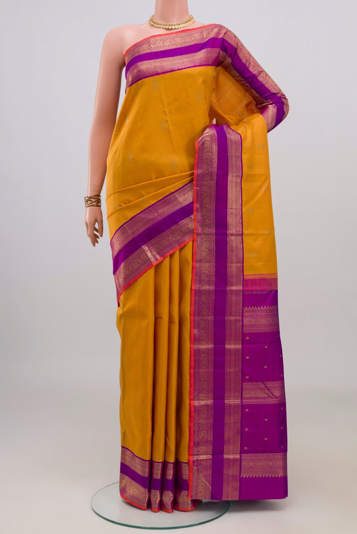 Pure Silk Pure Zari Mustard Kanjivaram Saree with Zari Butta on the body and Zari Border.  displayed on a mannequin