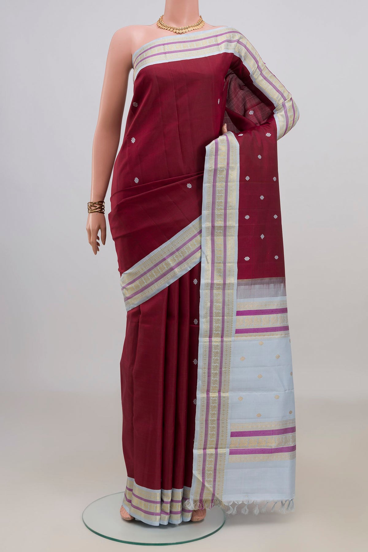 Pure Silk Maroon Kanjivaram Saree with Thread Butta on the body and Zari Border.  displayed on a mannequin