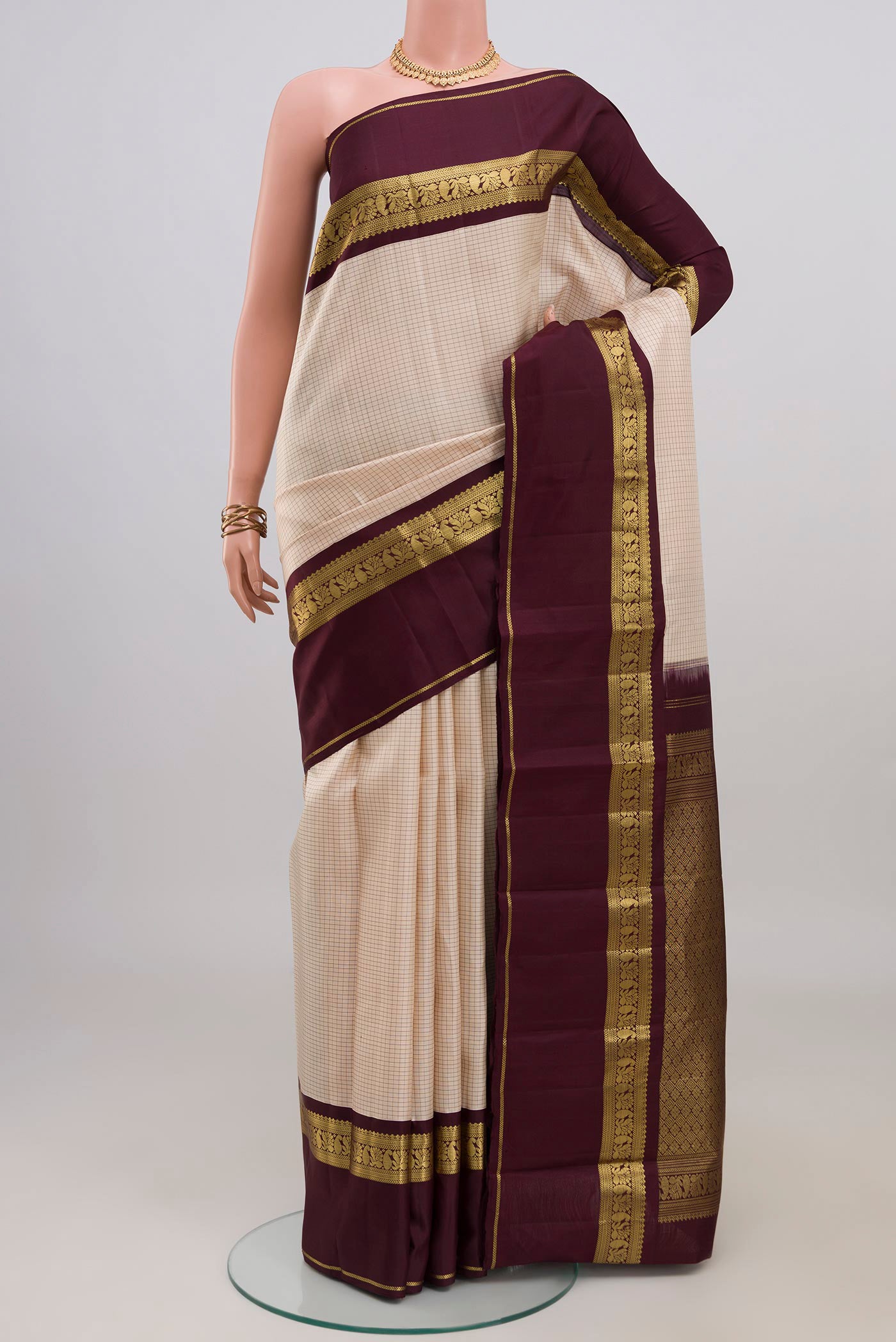 Cream Kanjivaram Silk Saree with Checked design on the body and Zari Border.  displayed on a mannequin