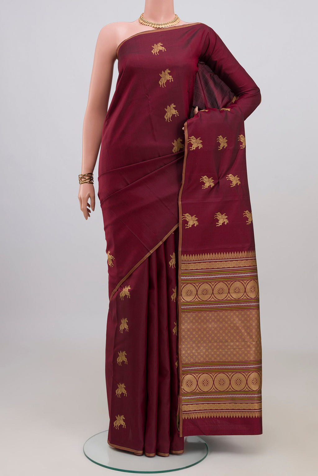 Pure Silk Pure Zari Maroon Kanchipuram Saree with Zari Butta on the body and Thin Zari Line.  displayed on a mannequin