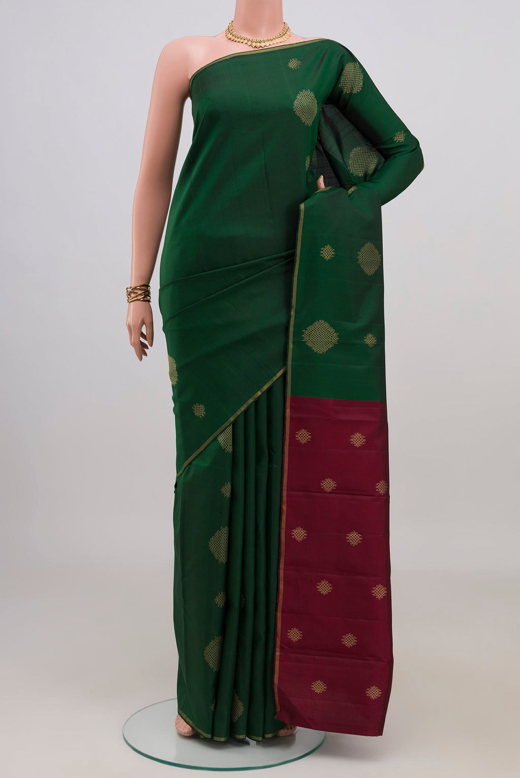 Bottle Green Kanchipuram Silk Saree with Zari Butta on the body and Thin Zari Line.  displayed on a mannequin