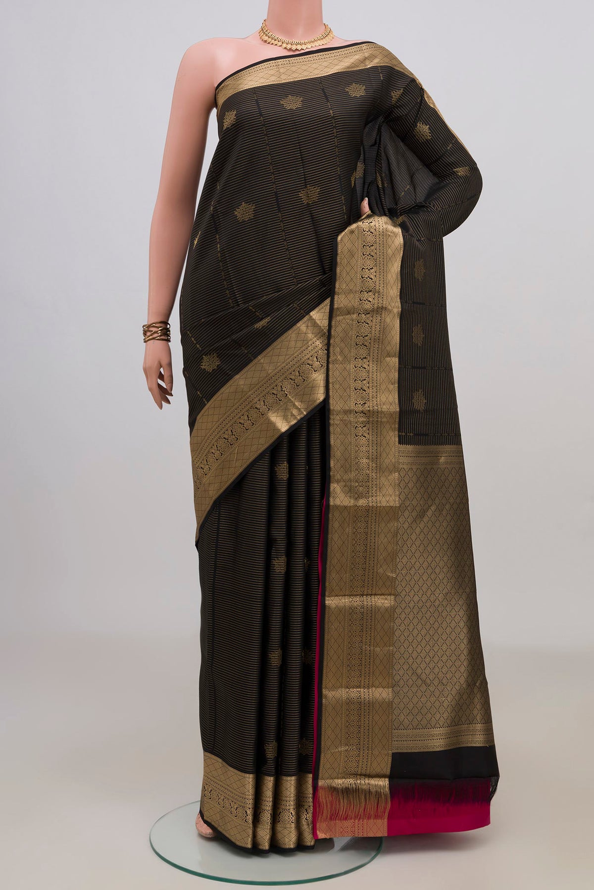 Pure Silk Black Kanchipuram Saree with Zari Butta on the body and Zari Border.  displayed on a mannequin