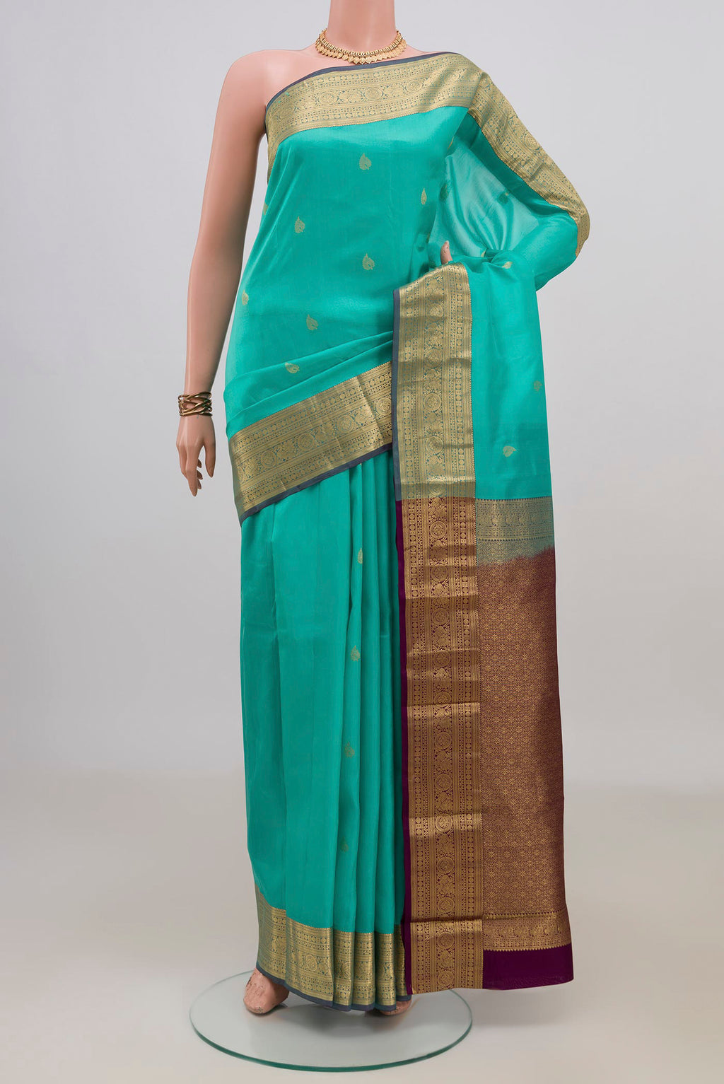 Pure Silk Turquoise Kanchipuram Saree with Zari Butta on the body and Zari Border.  displayed on a mannequin