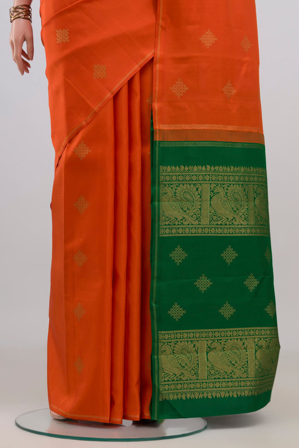 Pleats and pallu of Pure Silk Pure Zari Orange Kanchipuram Saree with Zari Butta on the body and Thin Zari Line. 