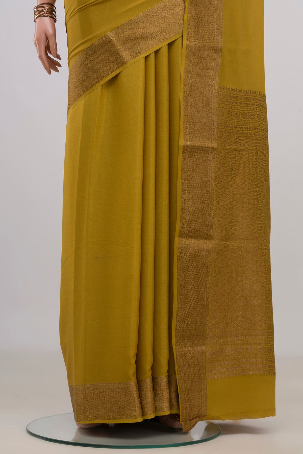 Pleats and pallu of Mustard Crepe Saree with Plain Body and Zari Border. 