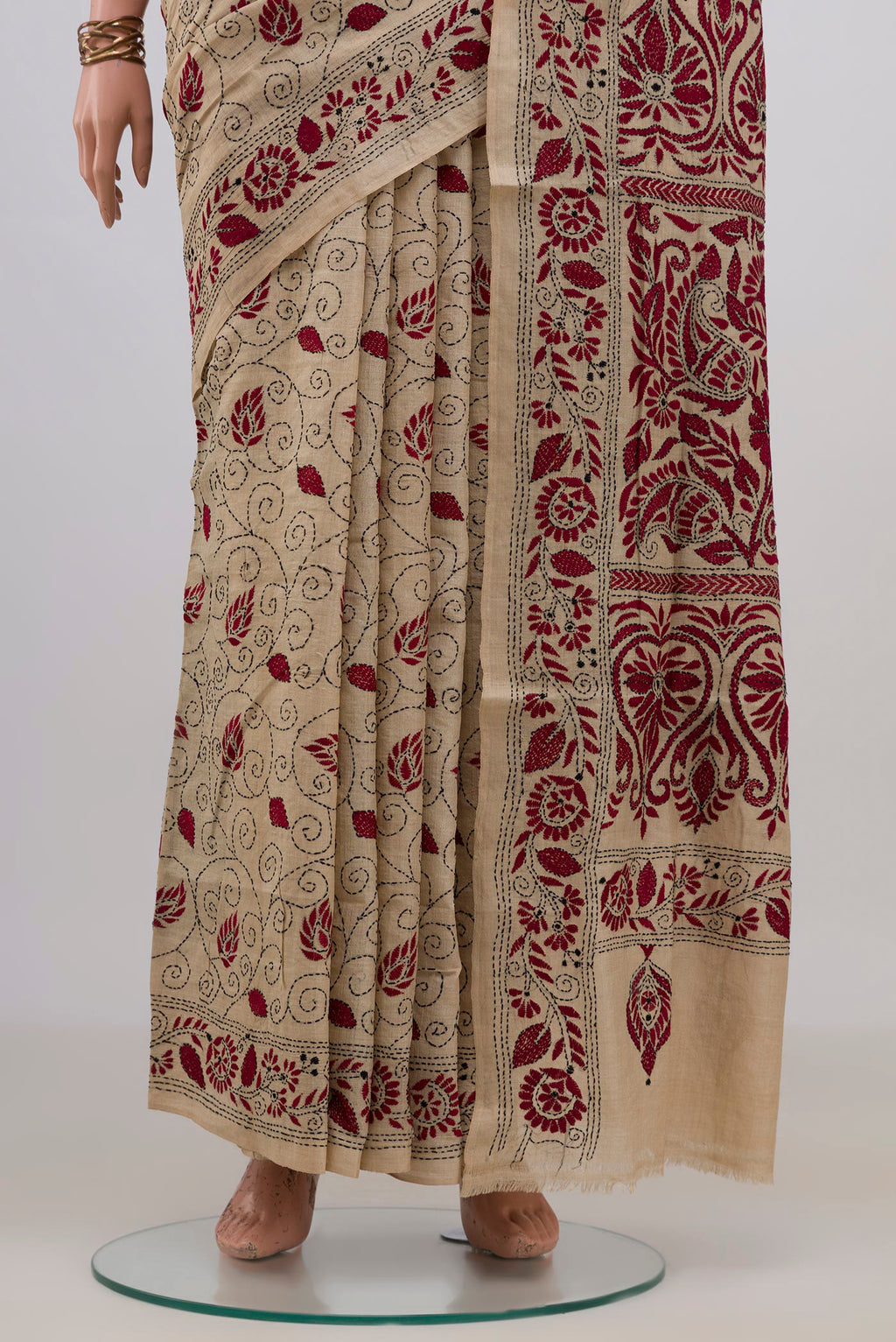 Pleats and pallu of Beige Tussar Saree with Kantha Work on the body and Embroidery Border. 