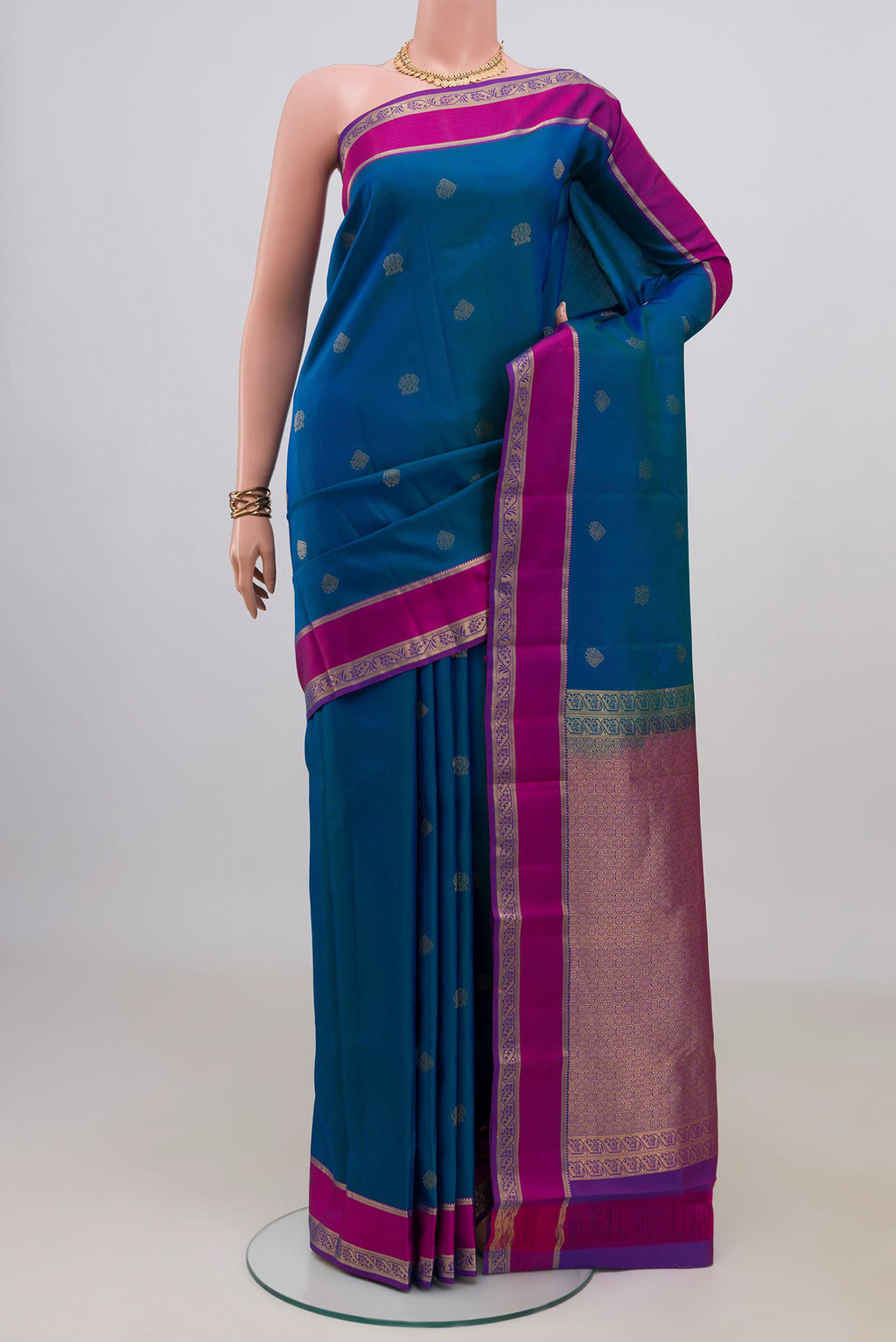 Pure Silk Peacock Blue Kanchipuram Saree with Zari Butta on the body and Zari Border.  displayed on a mannequin