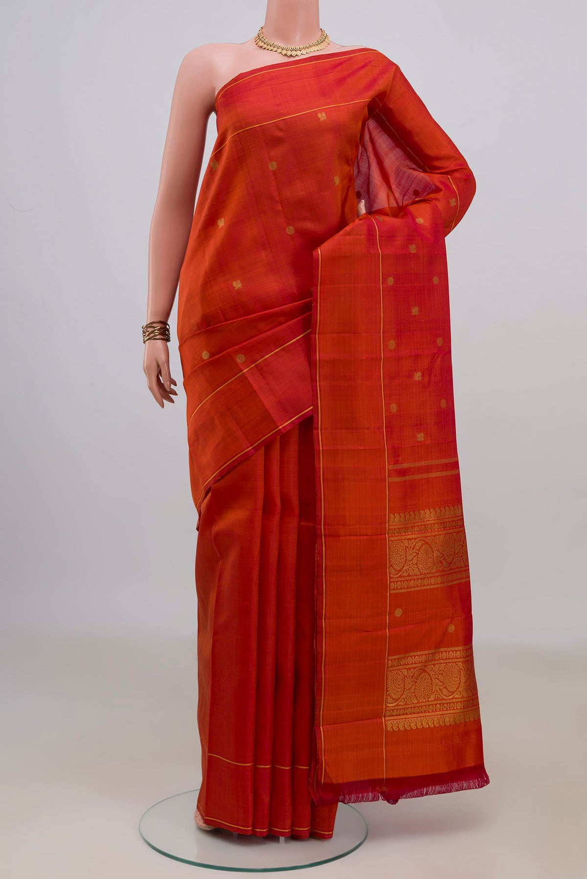 Pure Silk Pure Zari Rust Kanjivaram Saree with Zari Butta on the body and Thin Zari Line.  displayed on a mannequin