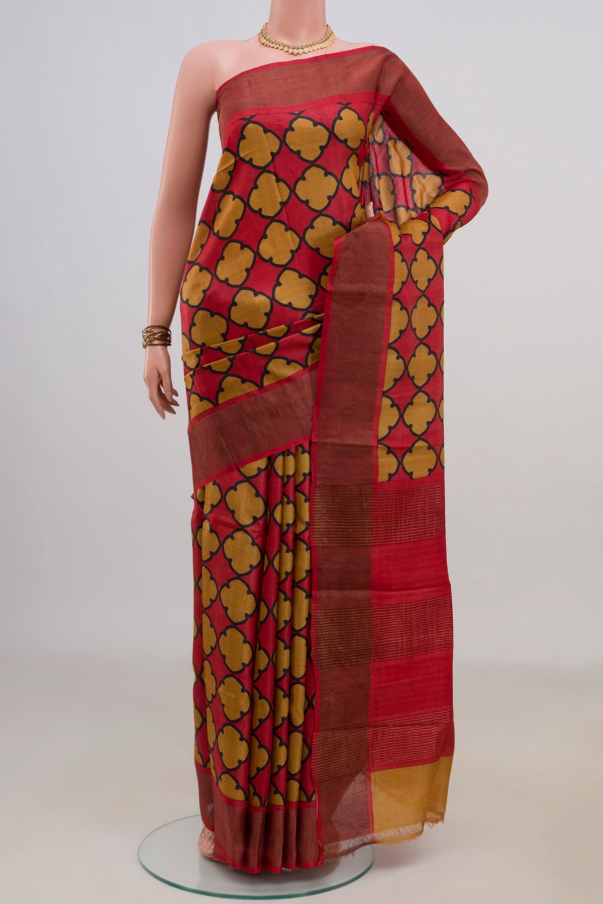 Red Tussar Saree with Printed design on the body and Zari Border.  displayed on a mannequin
