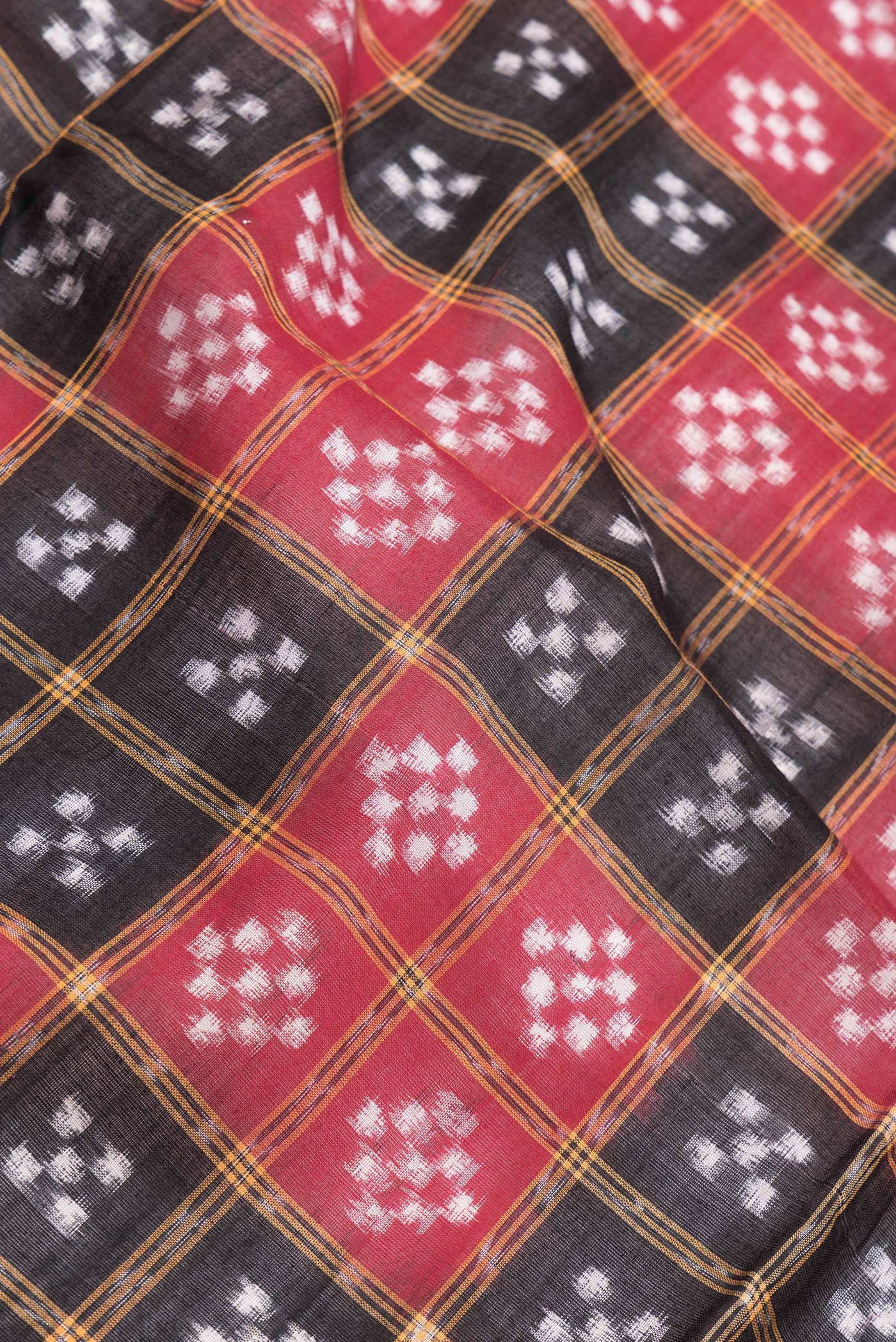 Close up of Black and Red Color Double Ikat Saree with Ikat Print on the body and Thread Border.  displaying folds