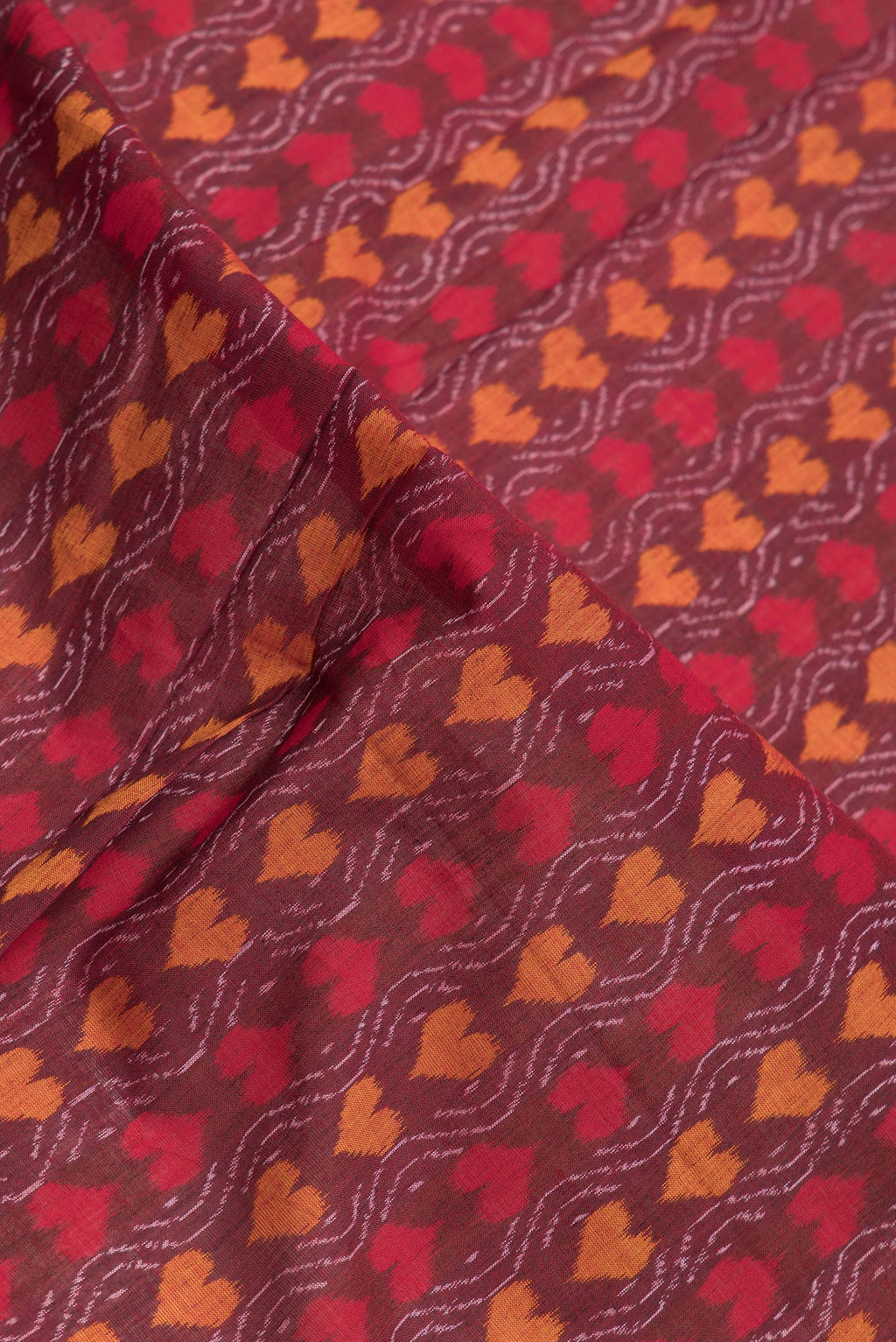 Close up of Maroon Dual Tone Double Ikat Saree with Ikat Print on the body and Thread Border.  displaying folds
