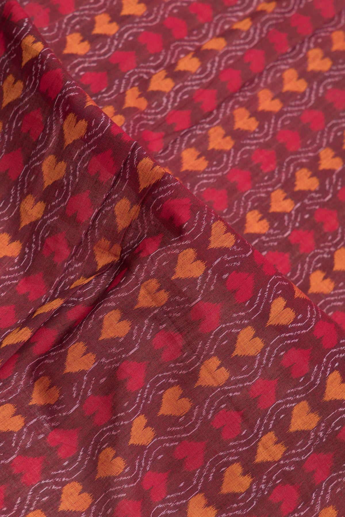 Close up of Maroon Dual Tone Double Ikat Saree with Ikat Print on the body and Thread Border.  displaying folds