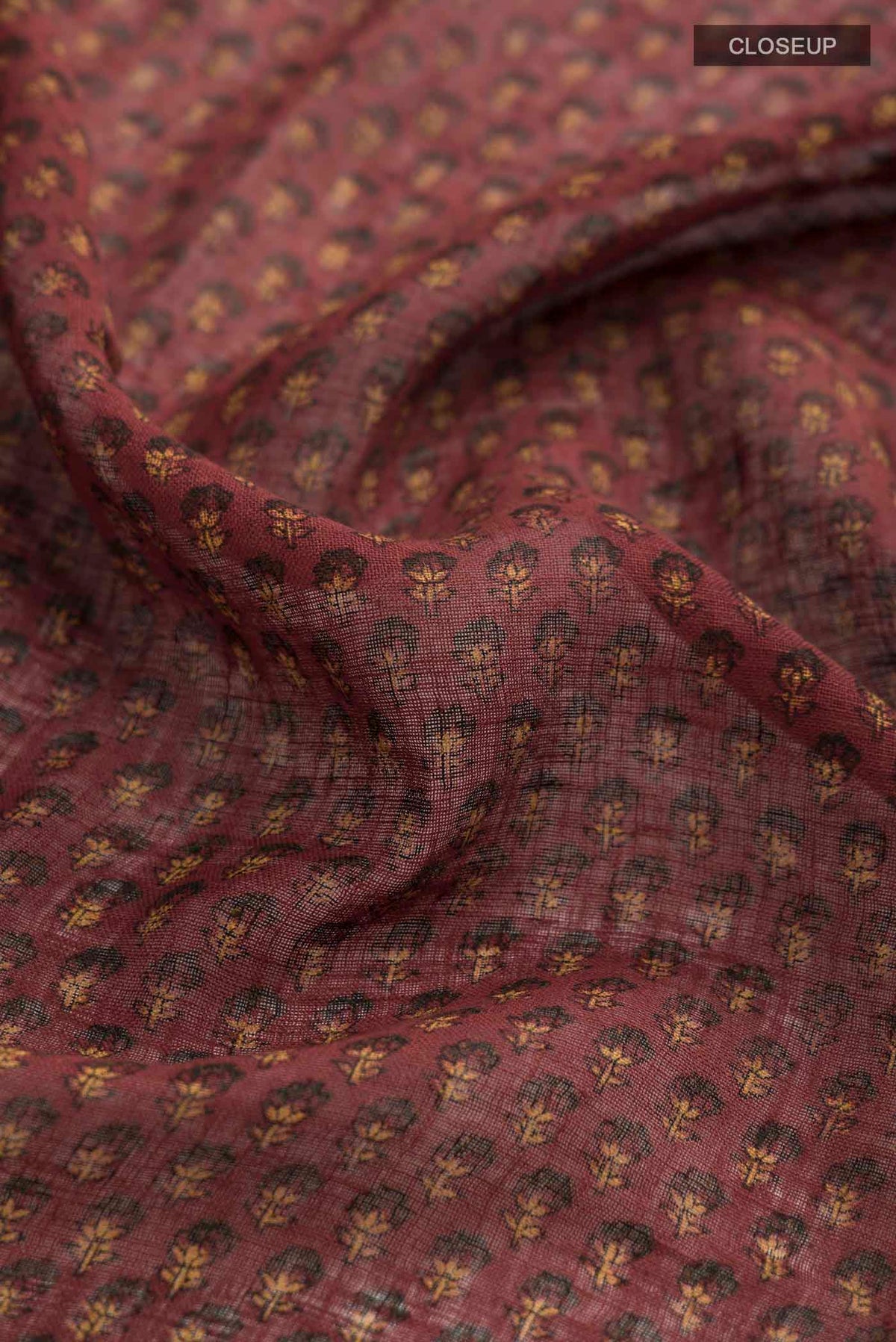 Close up of Rust Kalamkari Cotton Saree with Printed design on the body and Zari Border displaying folds
