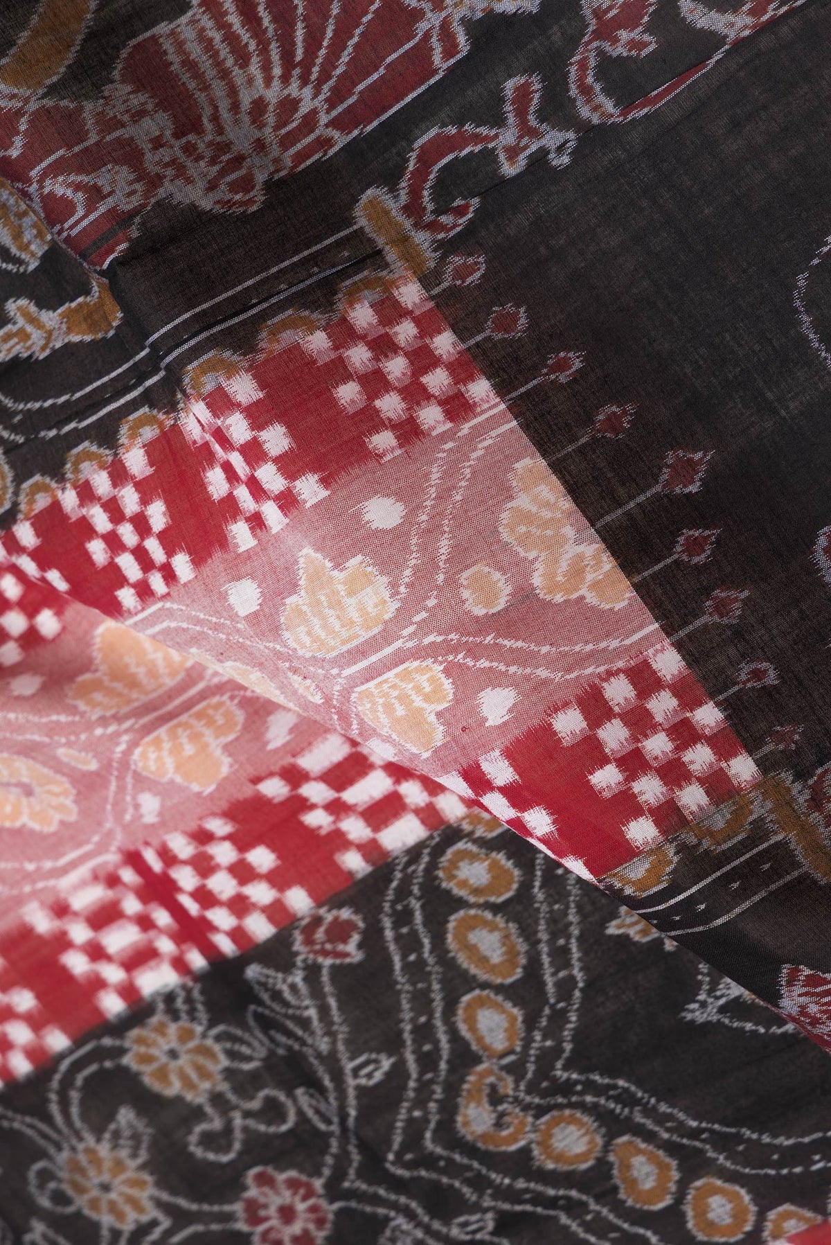 Close up of Black and Maroon Color Double Ikat Saree with Ikat Print on the body and Thread Border.  displaying folds