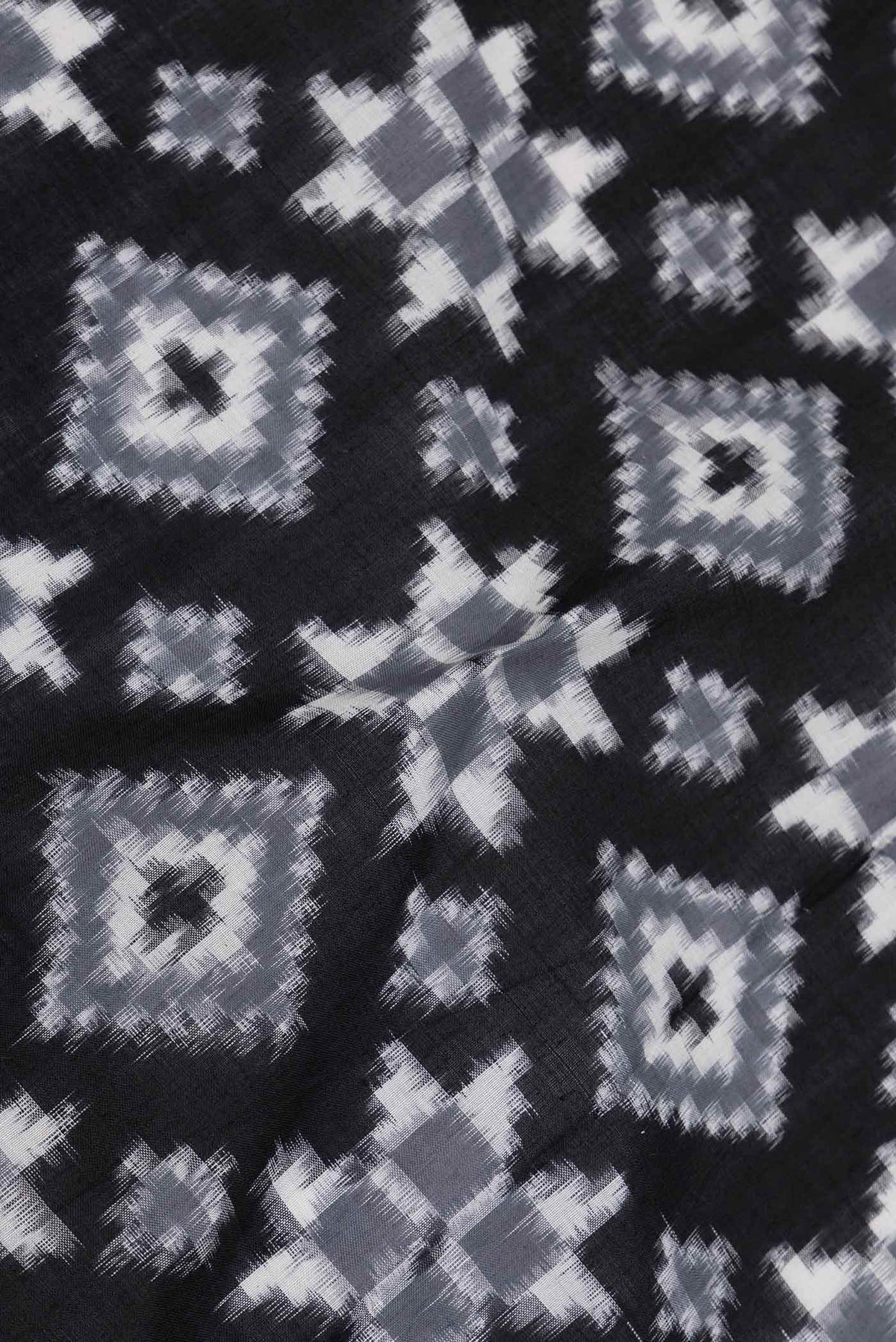 Close up of Black Dual Tone Double Ikat Saree with Ikat Print on the body and Plain Border displaying folds