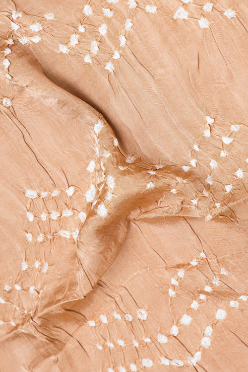Close up of Beige Blended Satin Crepe Saree with Bandhani Print on the body and Printed Border.  displaying folds