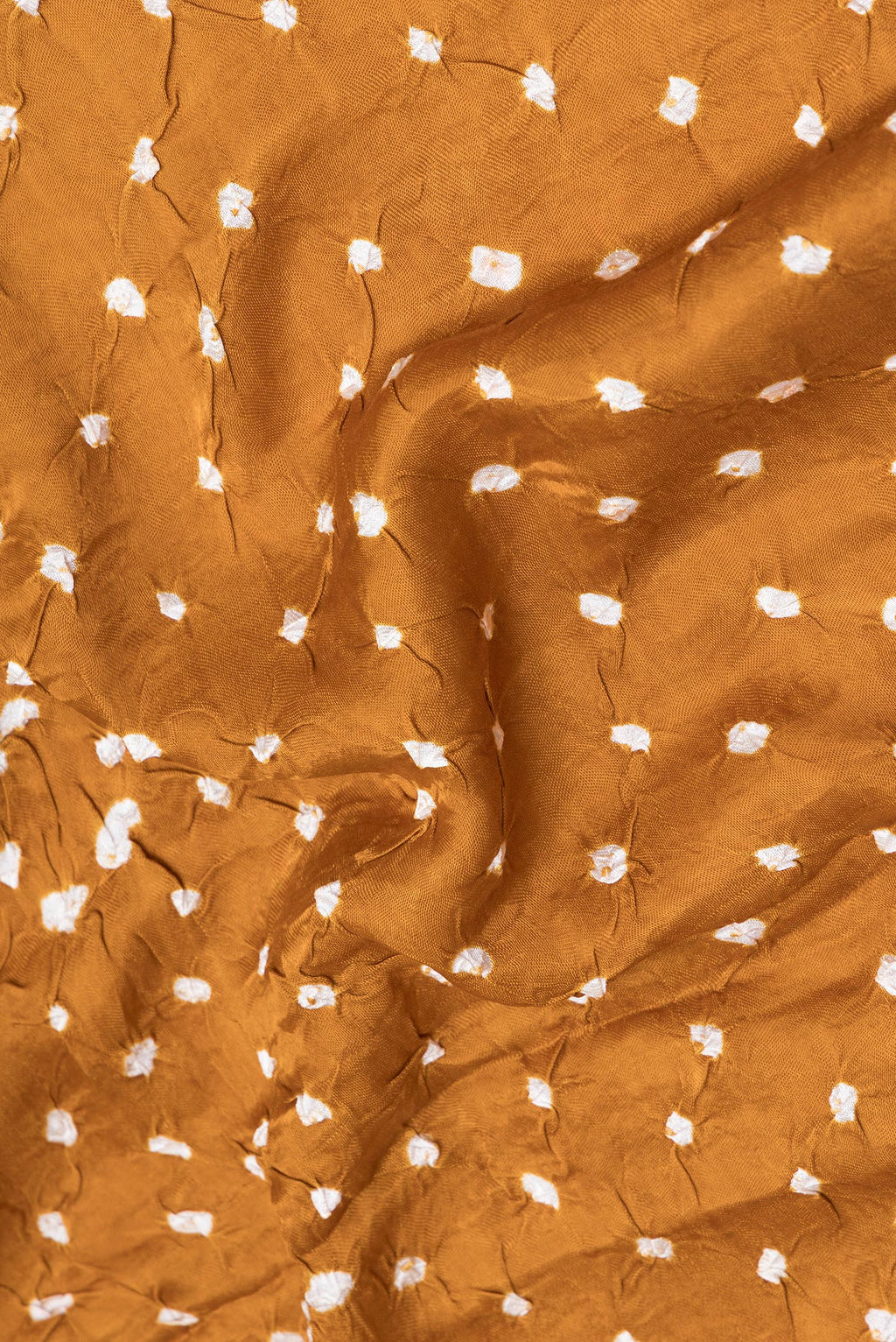 Close up of Mustard Blended Satin Crepe Saree with Bandhani Print on the body and Printed Border.  displaying folds