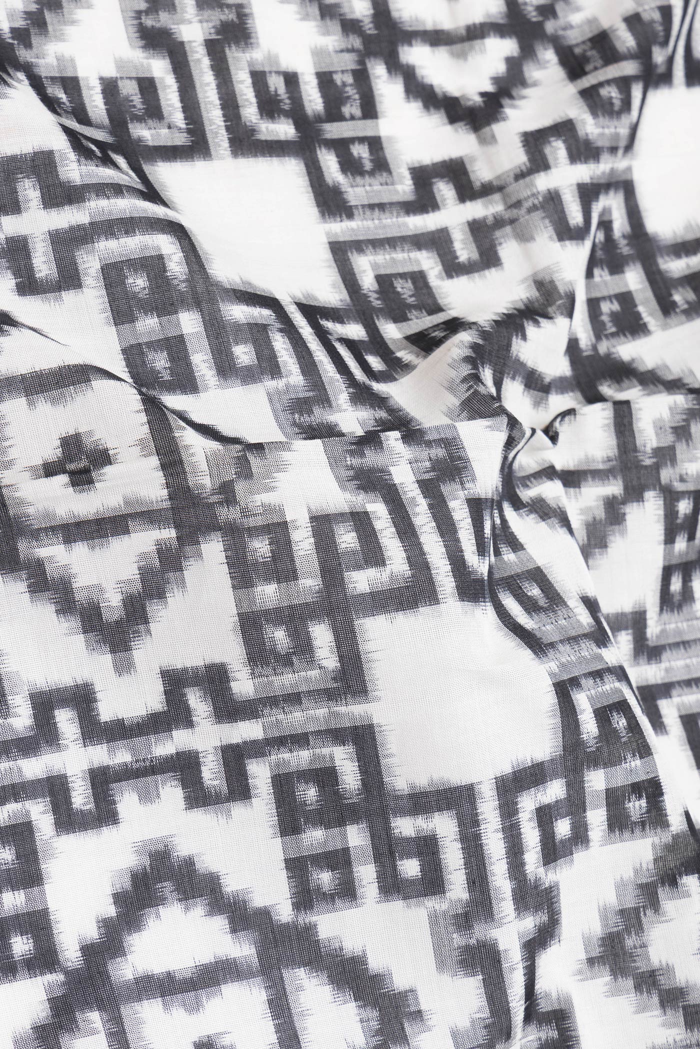 Close up of Black and White Color Double Ikat Saree with Ikat Print on the body and Thread Border.  displaying folds