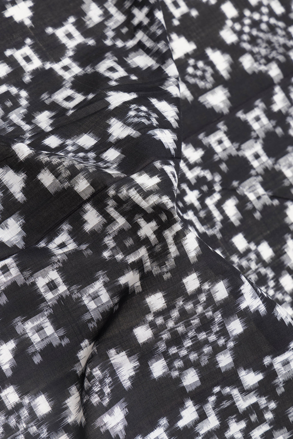 Close up of Black Dual Tone Double Ikat Saree with Ikat Print on the body and Thread Border.  displaying folds